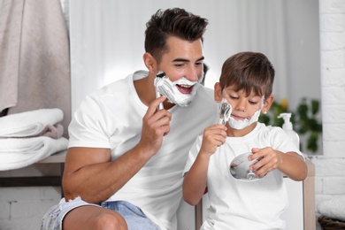 Photo of Father and son having fun while shaving in bathroom