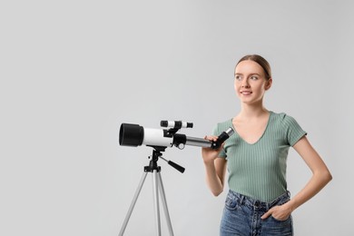 Young astronomer with telescope on grey background, space for text