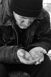 Poor homeless senior man holding coins outdoors. Black and white effect