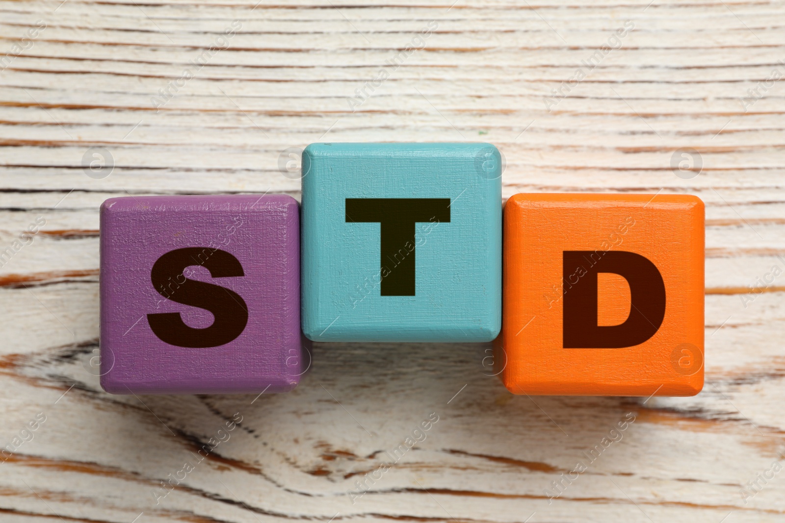 Photo of Abbreviation STD made with cubes on white wooden table, flat lay