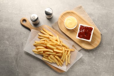 Delicious french fries served with sauces on grey table, flat lay