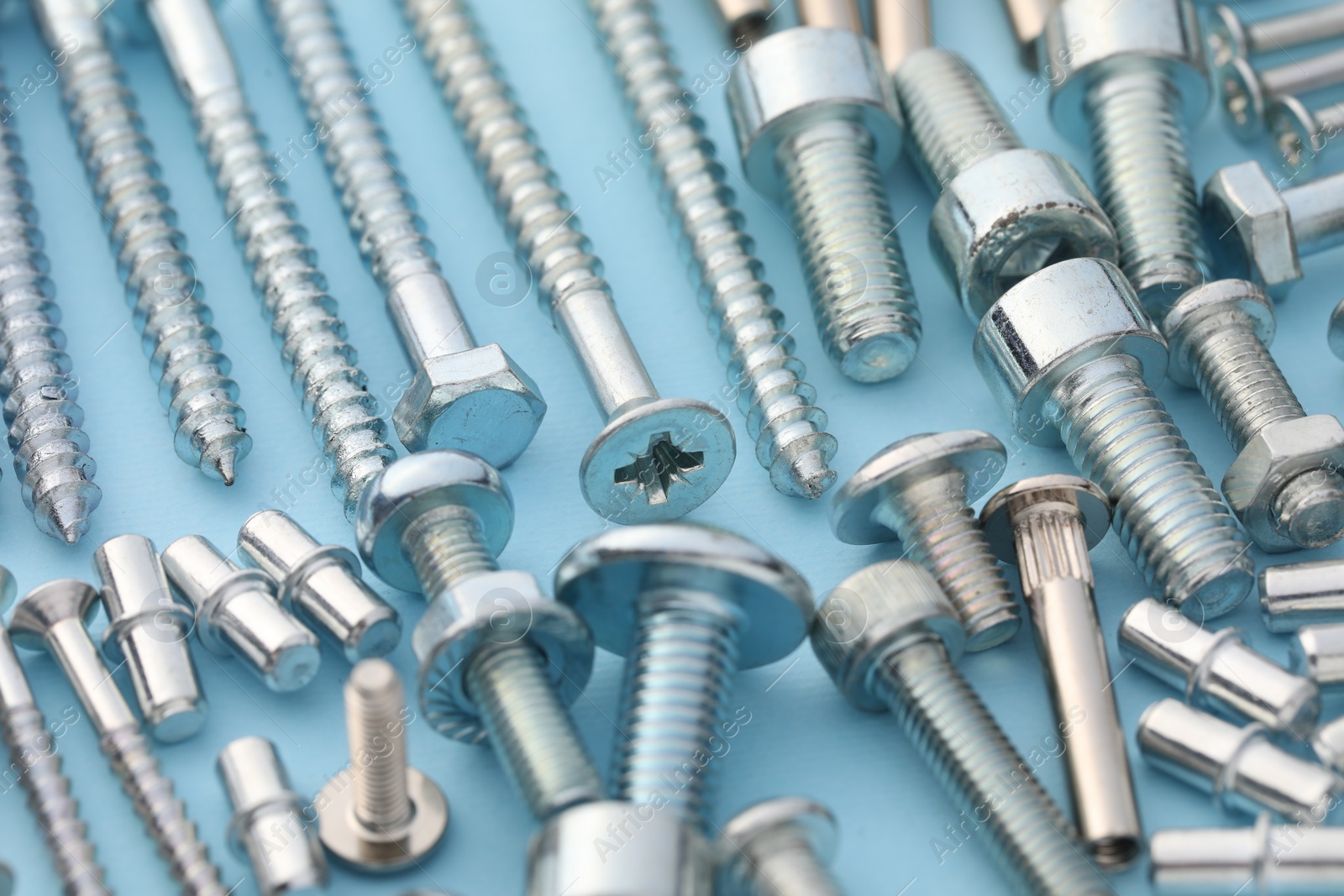 Photo of Many different fasteners on light blue background, closeup