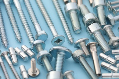 Many different fasteners on light blue background, closeup