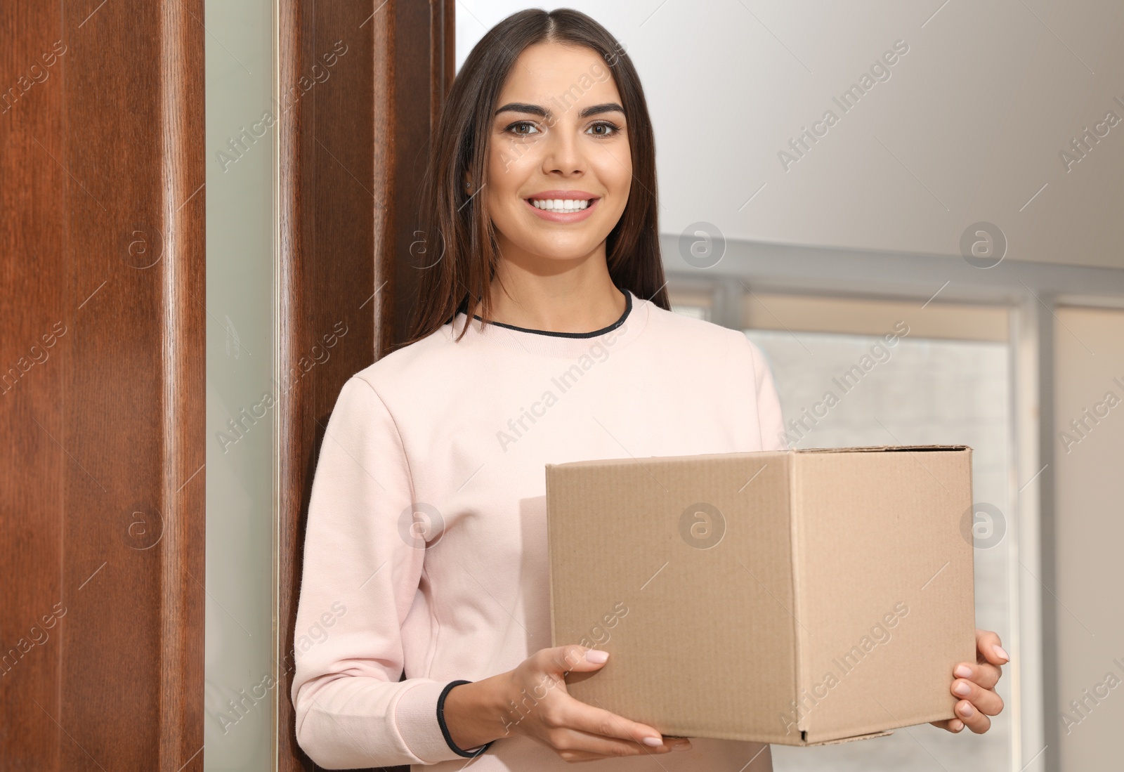 Photo of Portrait of smiling woman with parcel at door, mockup for design. Delivery service