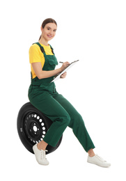 Professional auto mechanic with wheel and clipboard on white background
