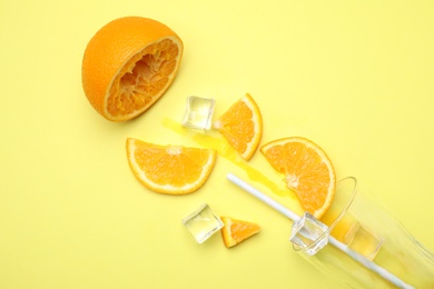 Photo of Cocktail illustration with orange, ice cubes and glass on yellow background, flat lay