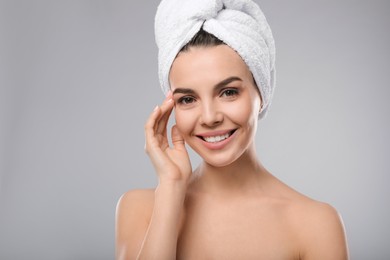 Photo of Happy young woman with towel on head against light grey background. Washing hair
