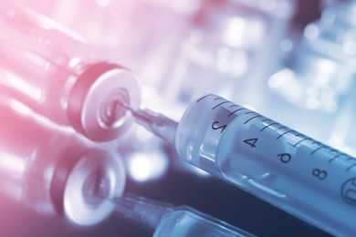 Image of Filling syringe with medicine from vial on mirror surface, closeup. Color toned