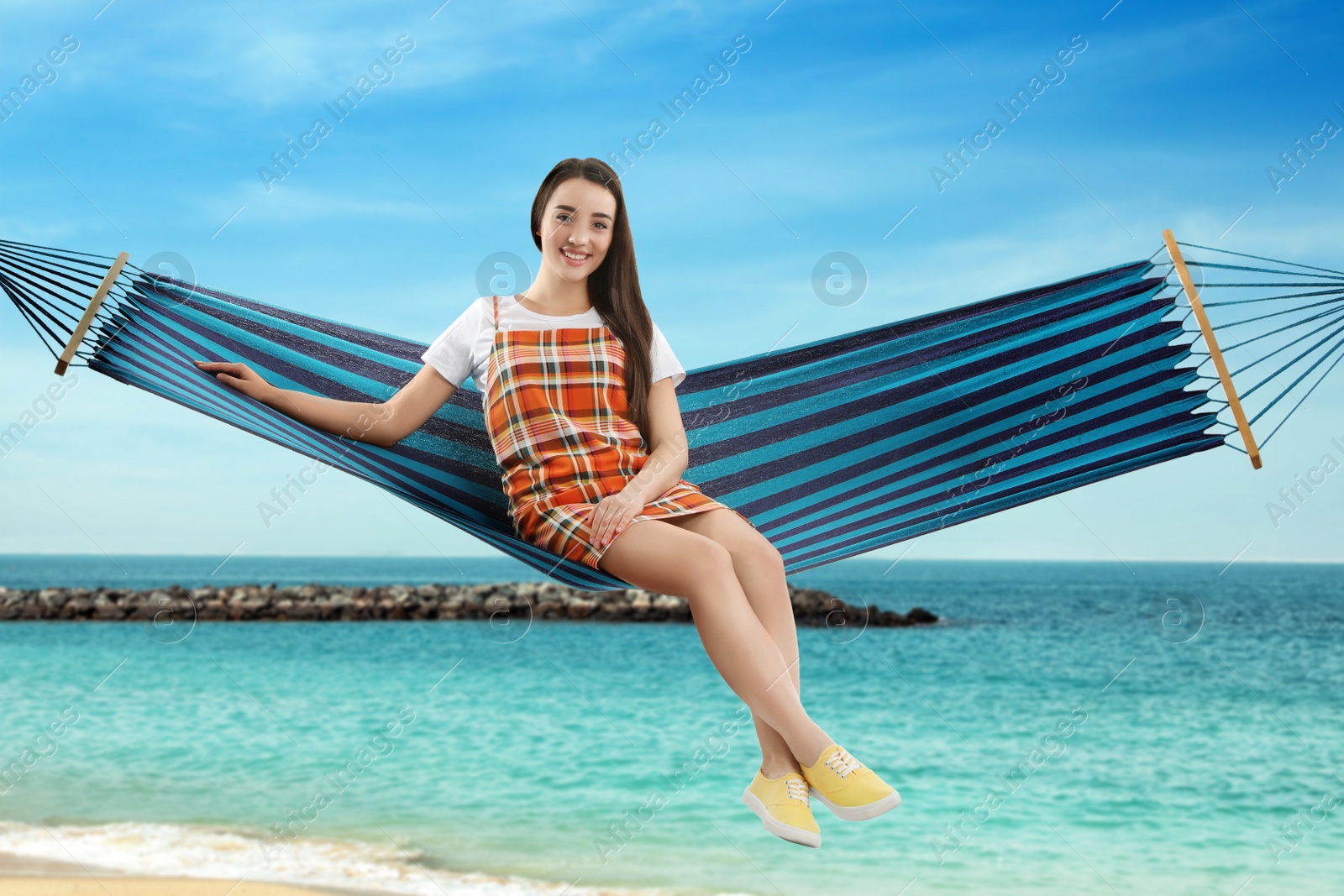 Image of Woman resting in hammock near sea on sunny day 