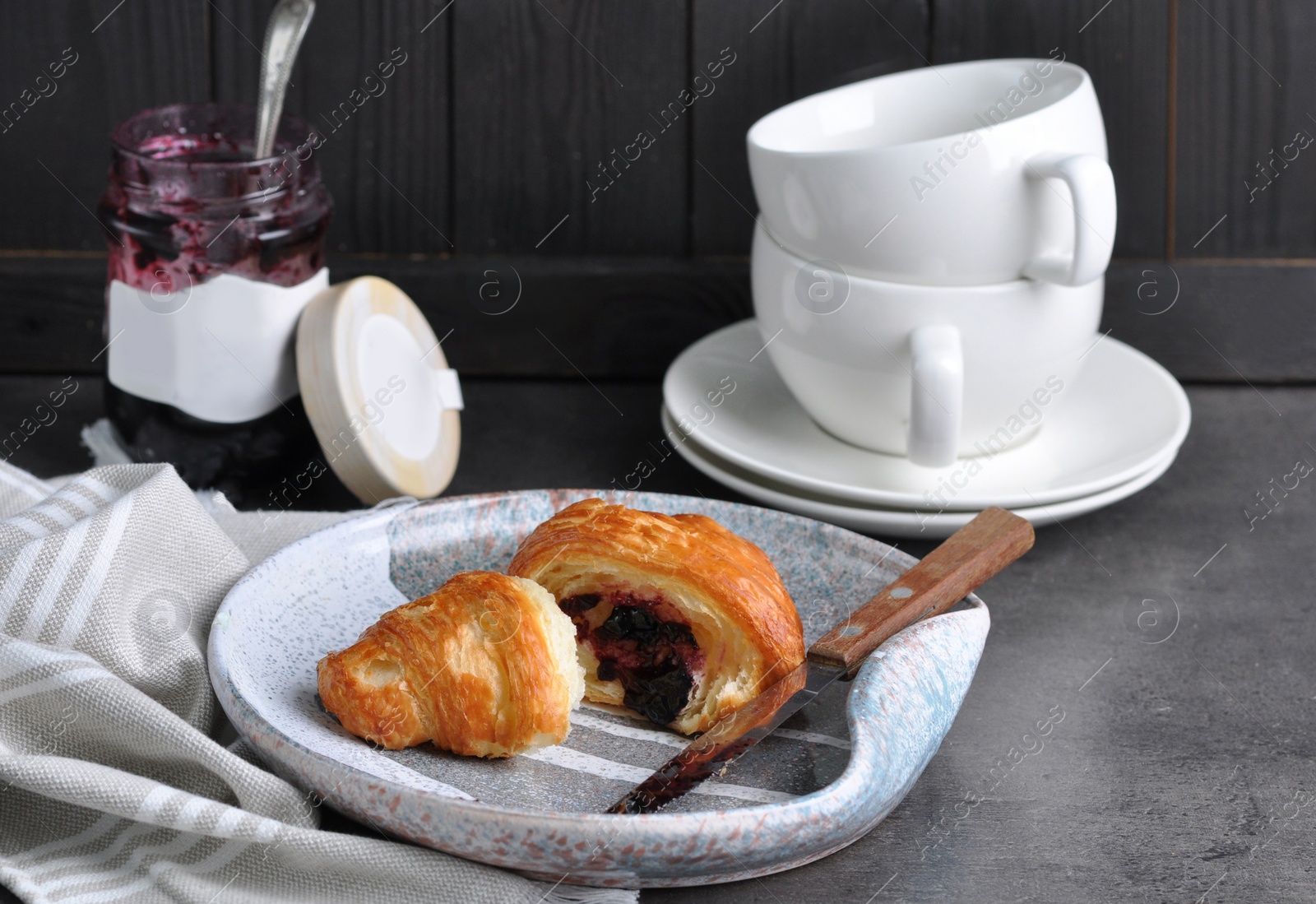 Photo of Tasty fresh croissant with jam on grey table