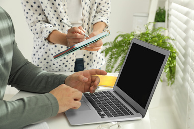 Colleagues working with calendar app on laptop in office, closeup