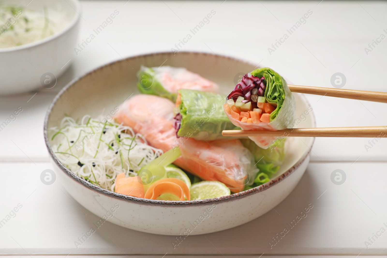 Photo of Delicious spring rolls wrapped in rice paper on white wooden table, closeup