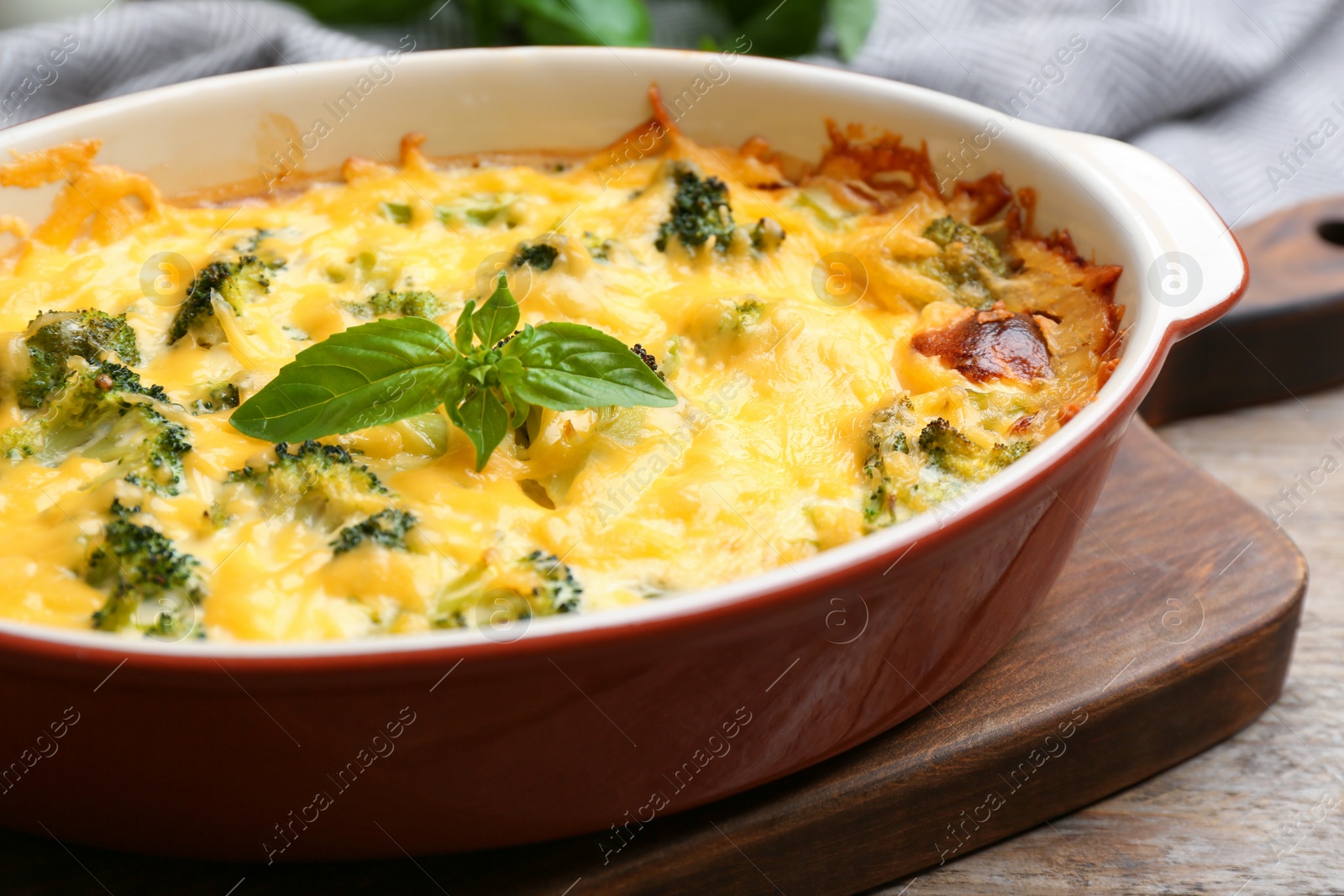 Photo of Tasty broccoli casserole in baking dish on wooden table, closeup