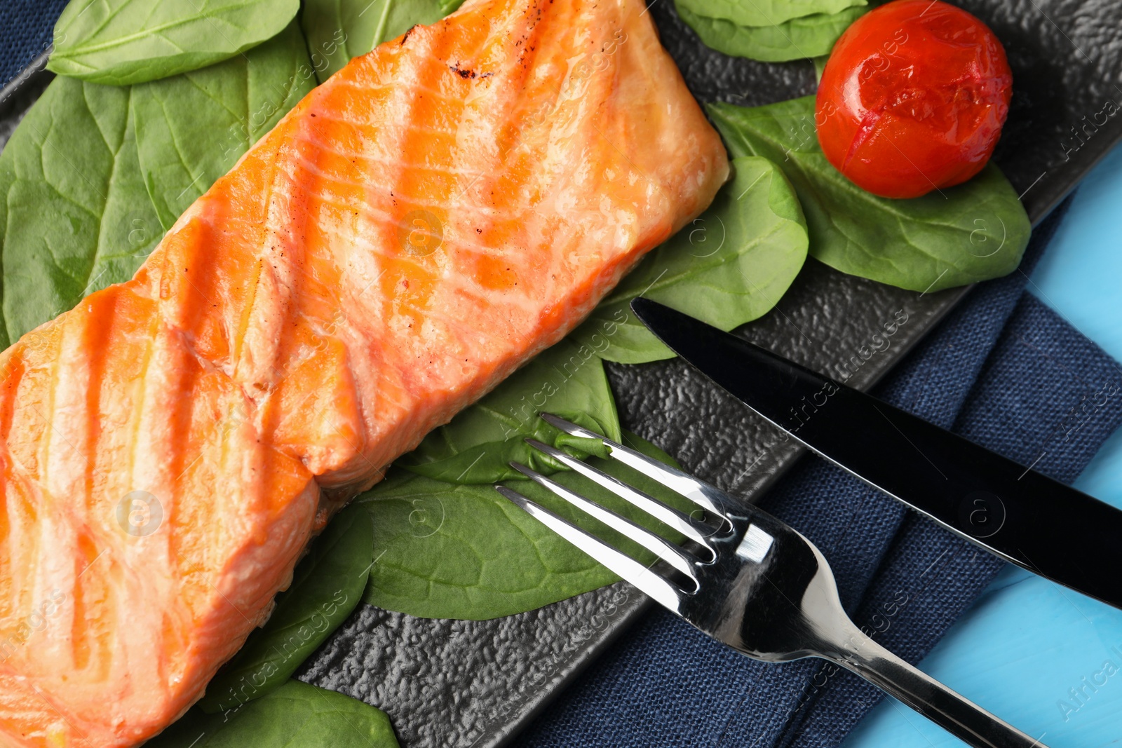 Photo of Tasty grilled salmon with spinach and tomato served on table, top view