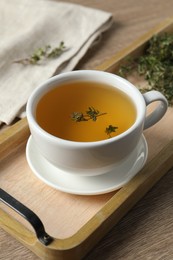 Photo of Cup of fresh thyme tea on wooden table