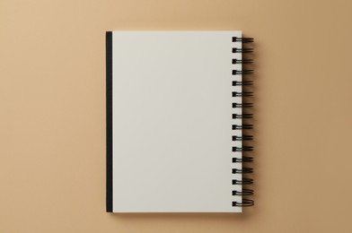 Spiral bound notebook on beige background, top view