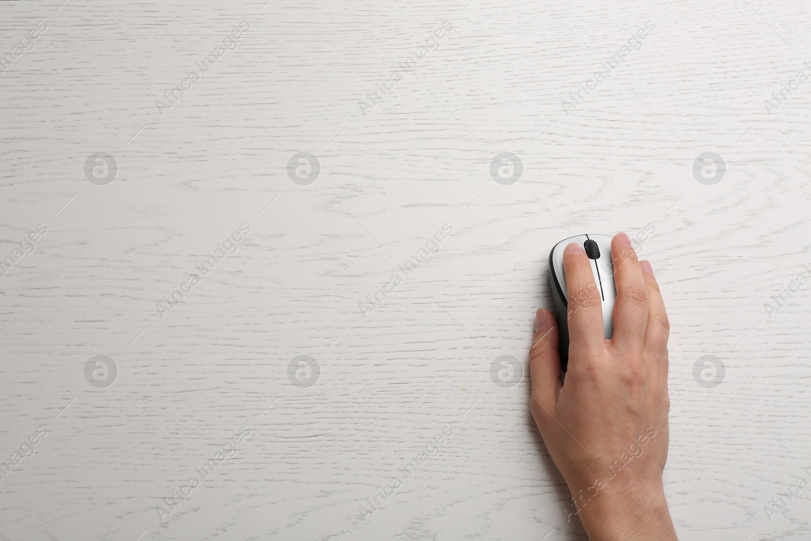 Photo of Woman using computer mouse on wooden table, top view. Space for text