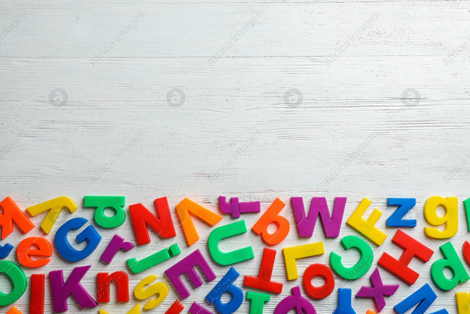 Photo of Plastic magnetic letters on wooden background, top view with space for text