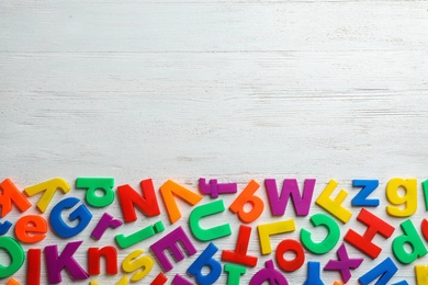 Plastic magnetic letters on wooden background, top view with space for text