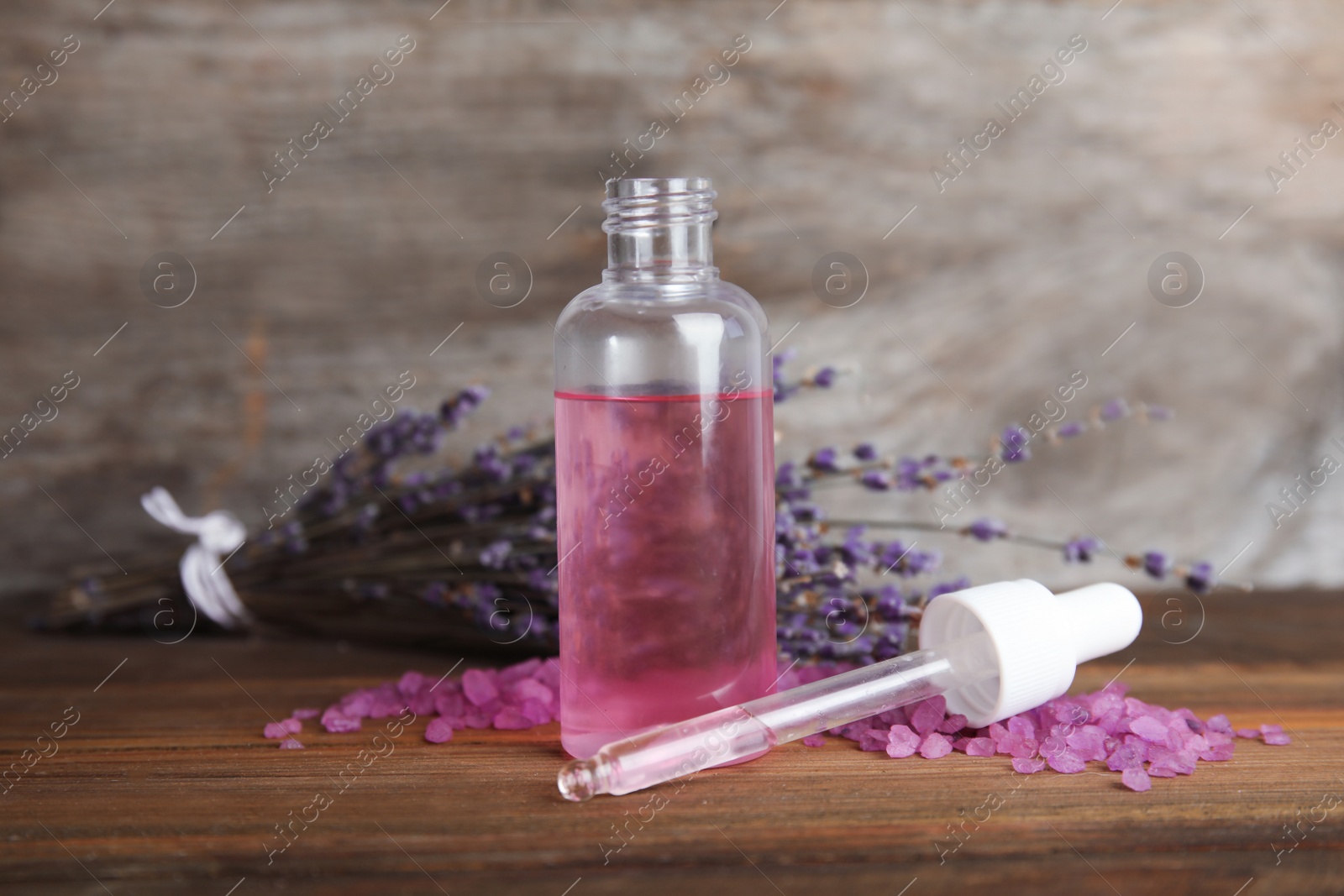 Photo of Bottle with aromatic lavender oil on wooden table