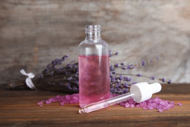 Photo of Bottle with aromatic lavender oil on wooden table