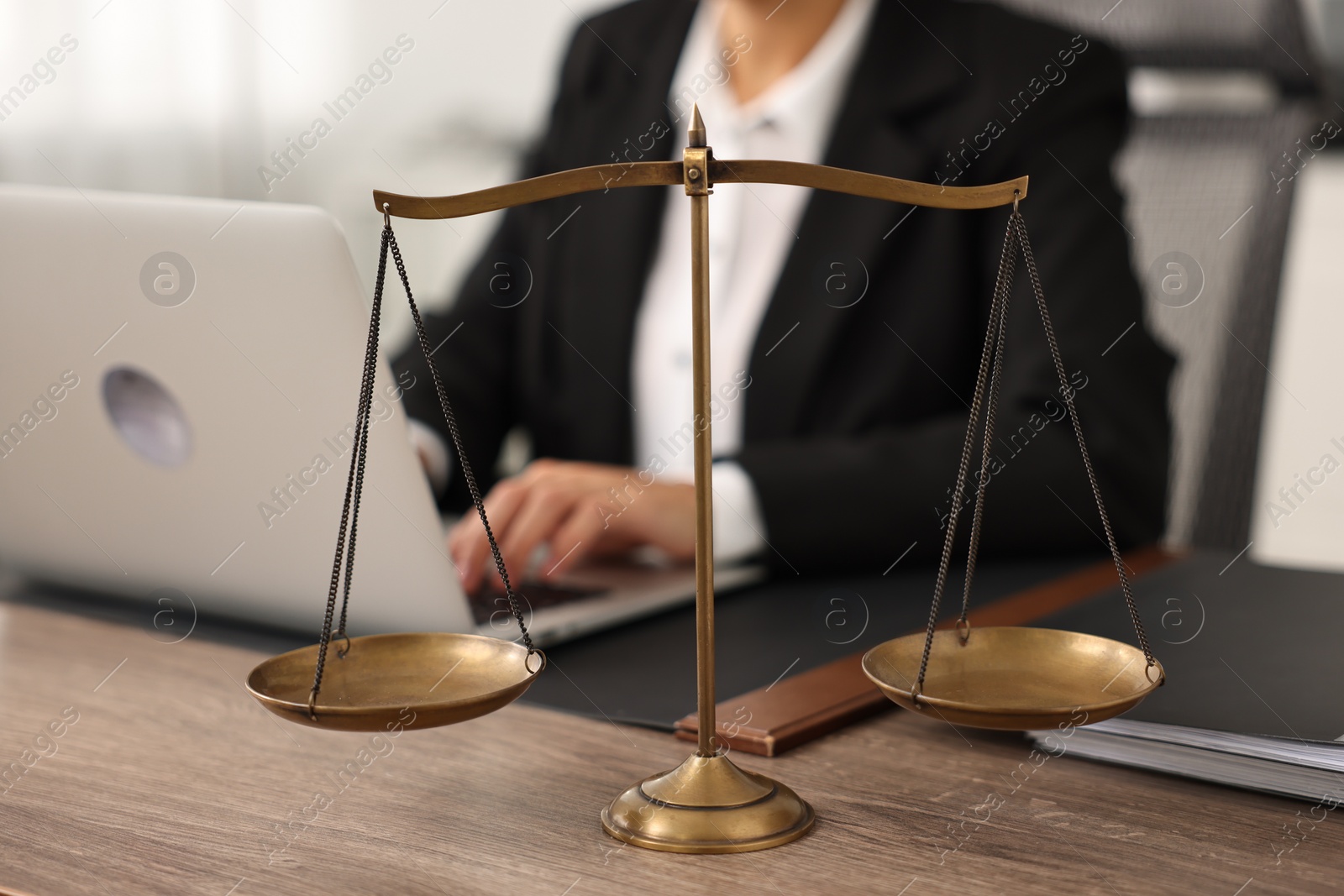Photo of Notary using laptop at workplace in office, focus on scales of justice