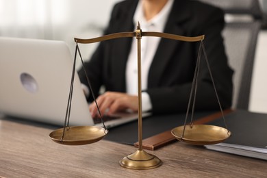 Photo of Notary using laptop at workplace in office, focus on scales of justice