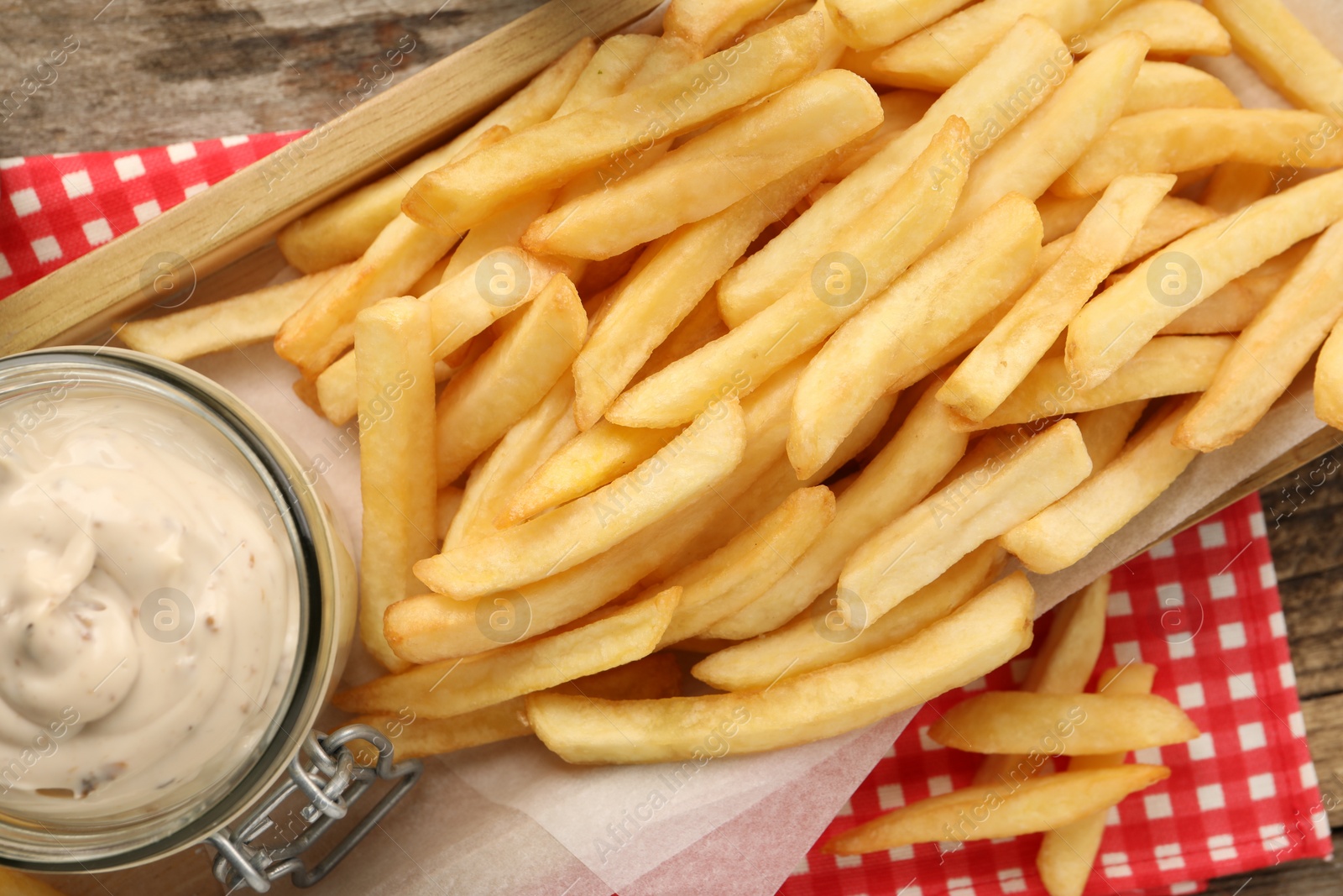 Photo of Delicious french fries served with sauce on wooden table, flat lay