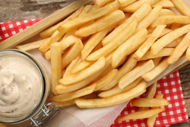 Delicious french fries served with sauce on wooden table, flat lay