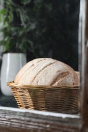Photo of Fresh homemade bread in wicker basket, view through window