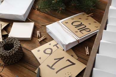 Composition with gift bags and paper notes on wooden table, closeup. Creating advent calendar
