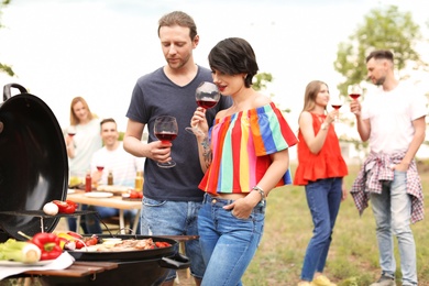 Photo of Young people having barbecue with modern grill outdoors