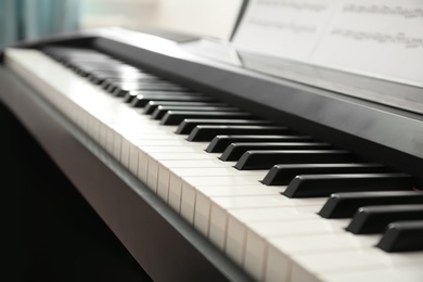 Modern piano with music sheets in room, closeup