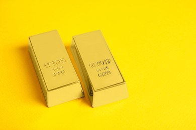 Photo of Shiny gold bars on yellow background, space for text