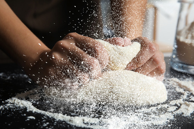 Image of Young woman kneading dough at table, closeup