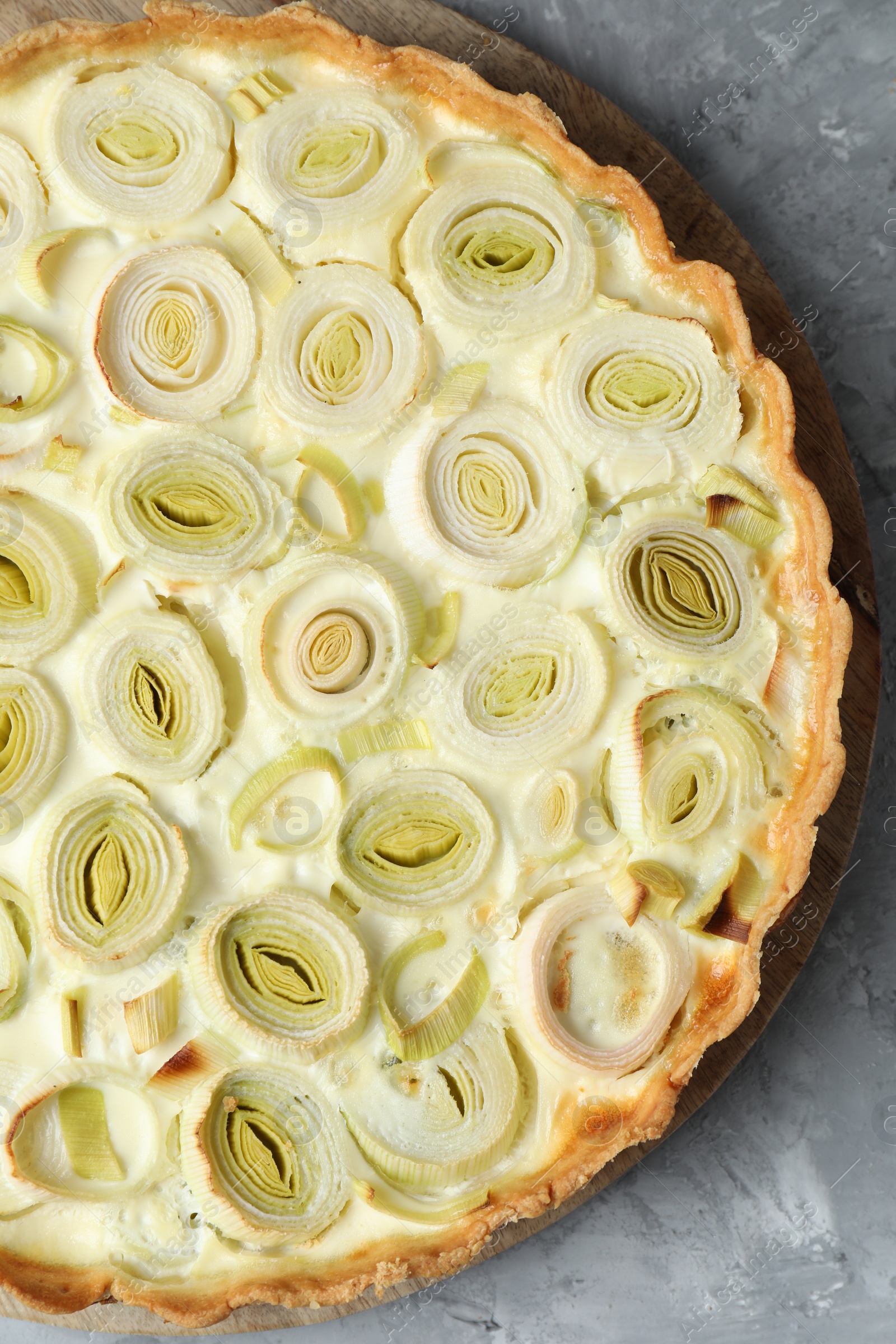 Photo of Freshly baked leek pie on grey textured table, top view