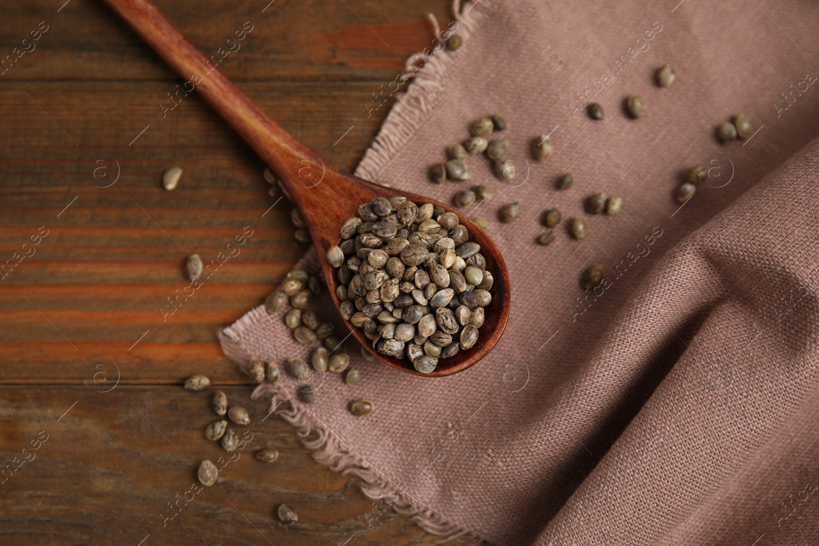 Photo of Spoon with organic hemp seeds on wooden table, flat lay