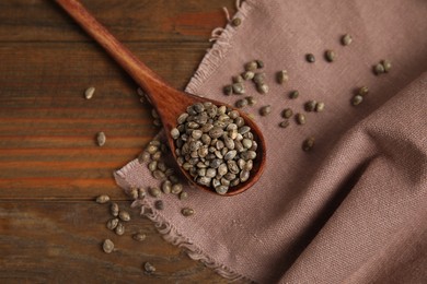 Spoon with organic hemp seeds on wooden table, flat lay