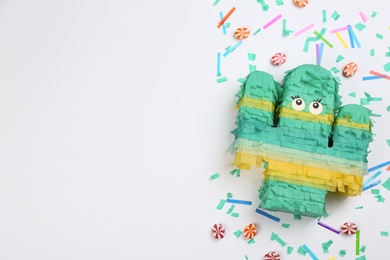 Composition with cactus shaped pinata and candies on white background, top view