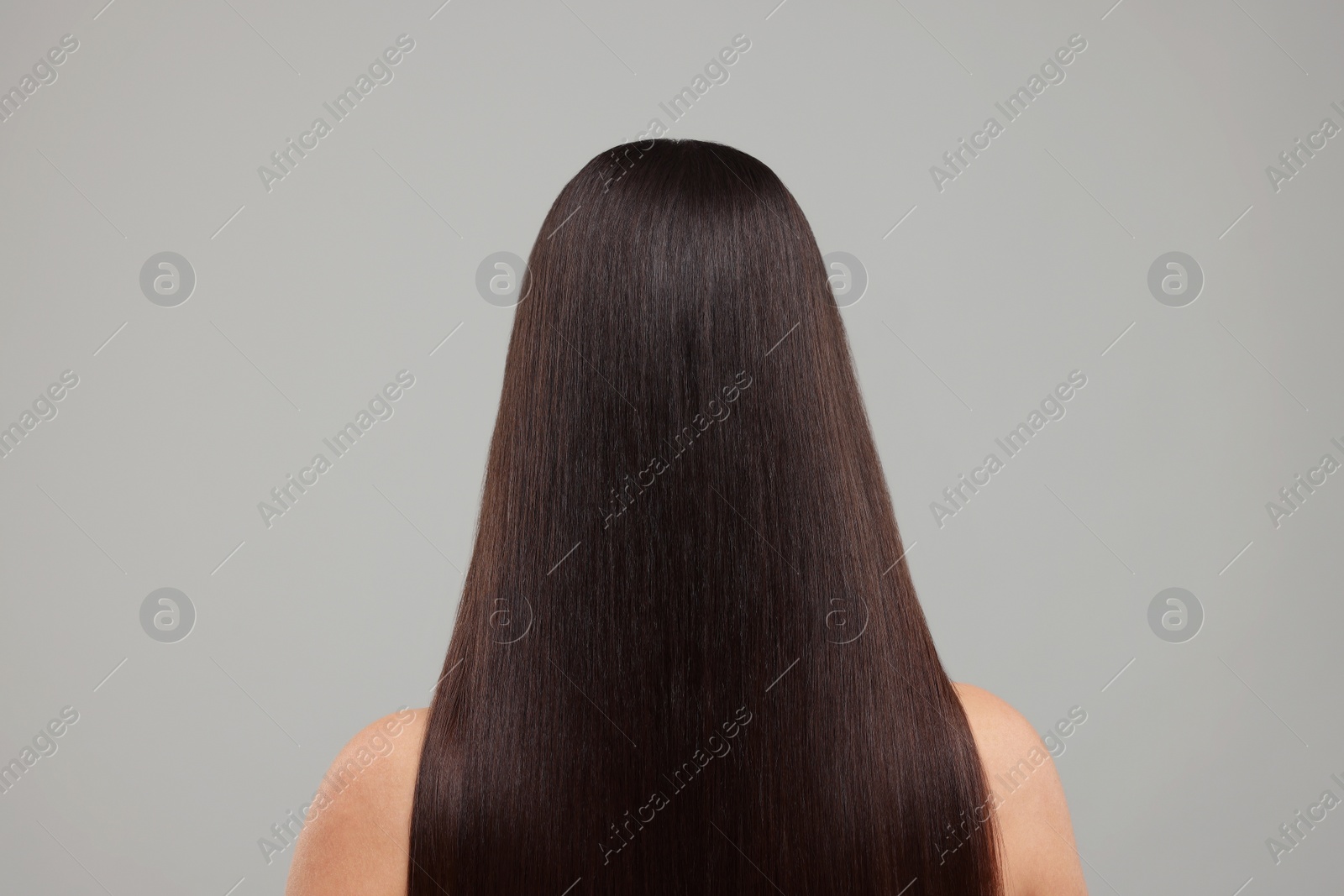 Photo of Woman with healthy hair after treatment on light grey background, back view