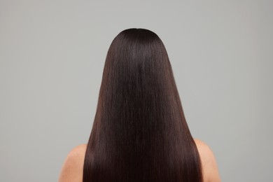 Photo of Woman with healthy hair after treatment on light grey background, back view