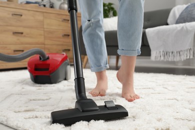 Photo of Woman cleaning carpet with vacuum cleaner at home, closeup