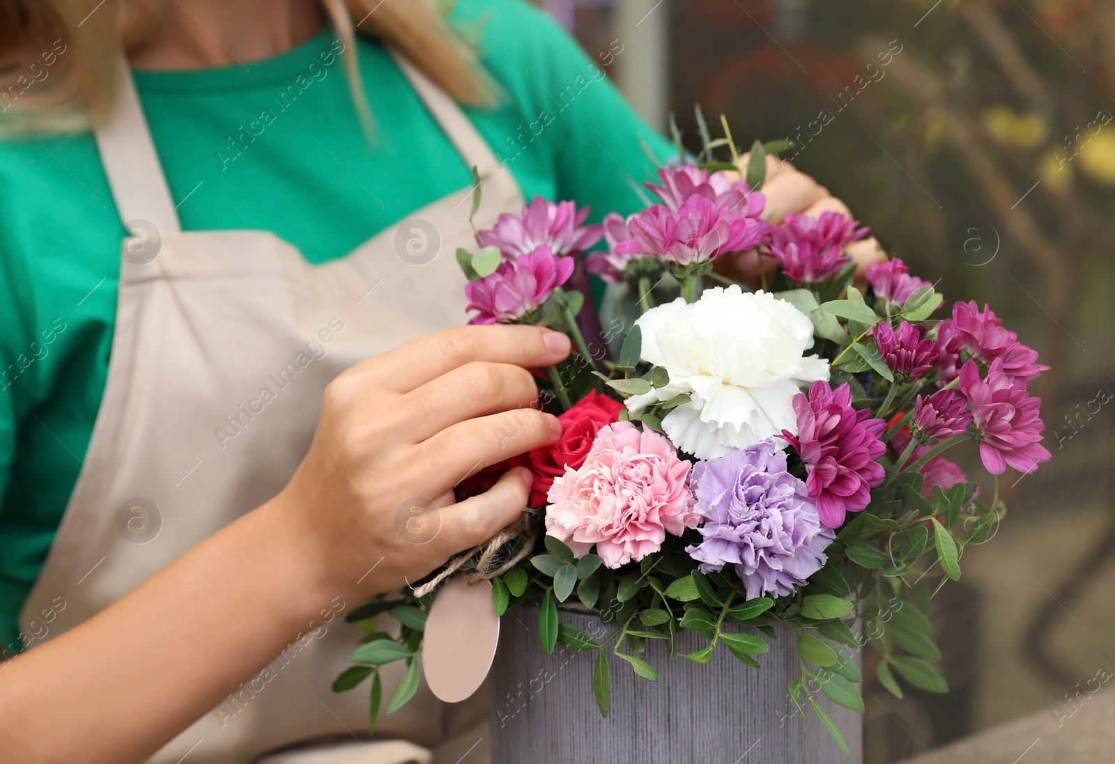 Photo of Female florist making beautiful bouquet in flower shop, closeup