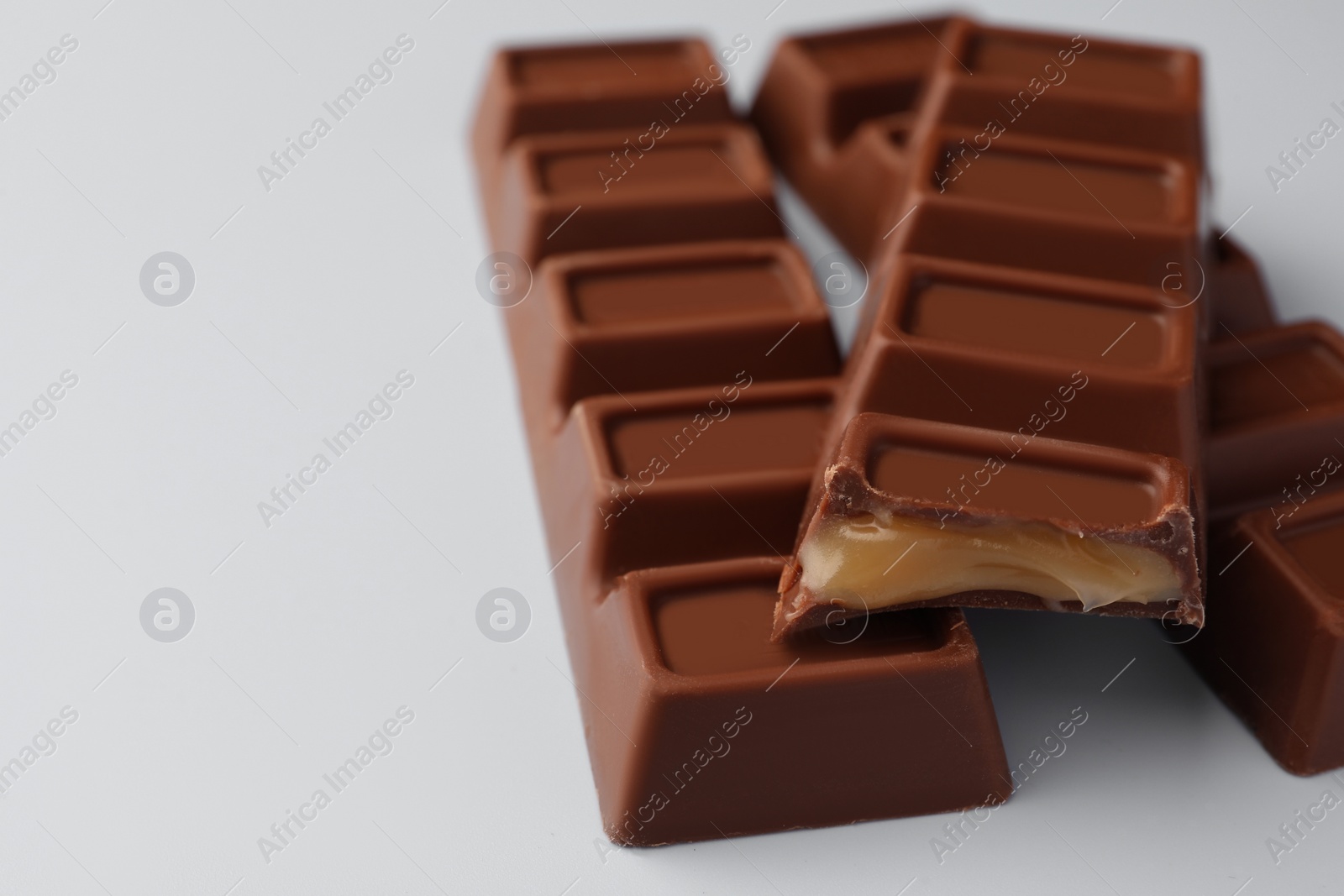 Photo of Delicious chocolate bars on light blue background, closeup