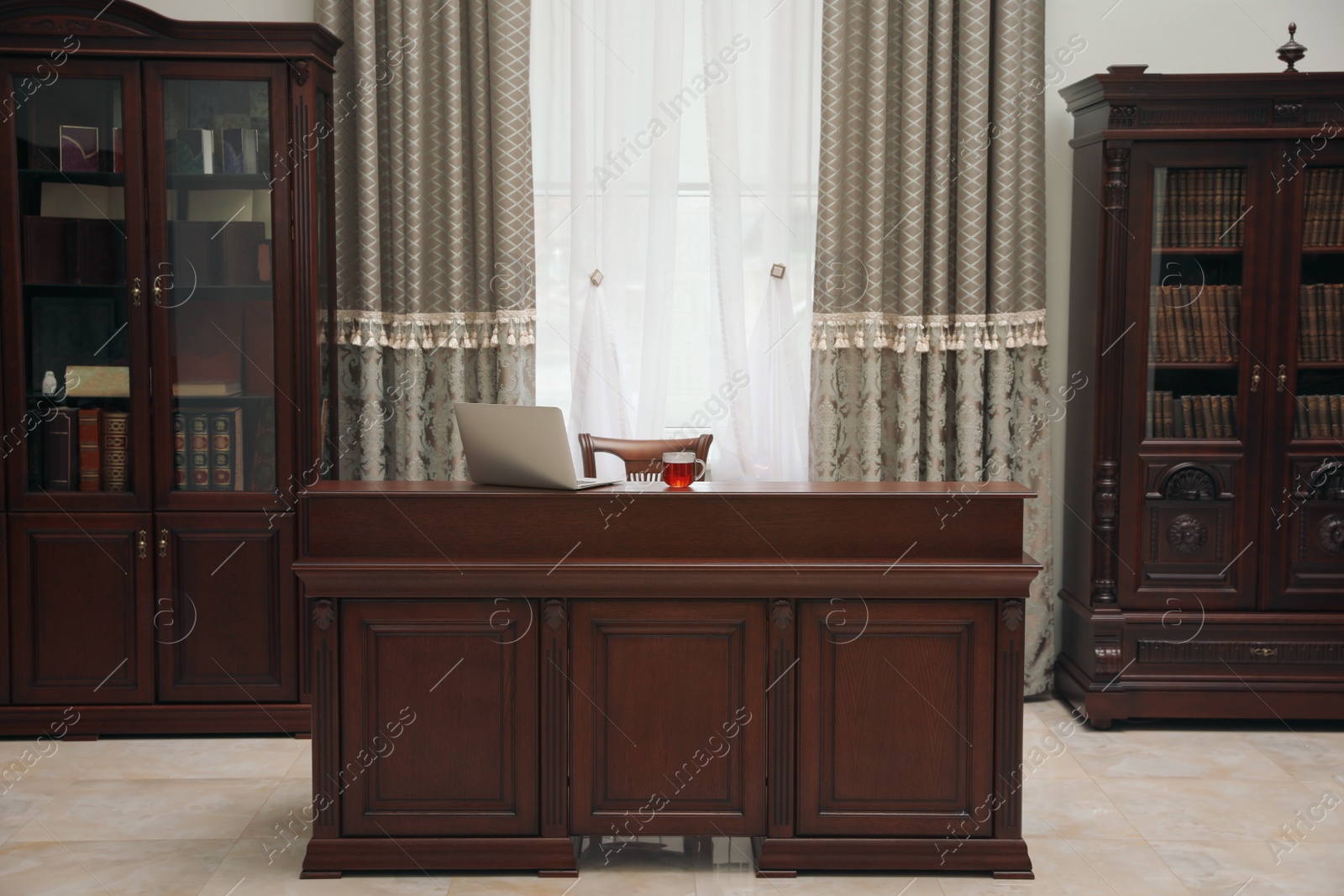 Photo of Library reading room interior with wooden bookcases and laptop on table