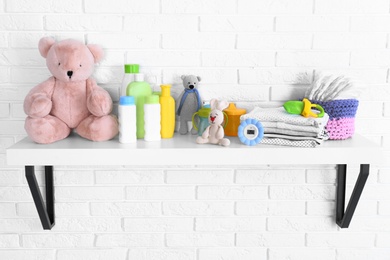 Baby accessories on shelf near white brick wall