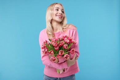 Beautiful young woman on light blue background