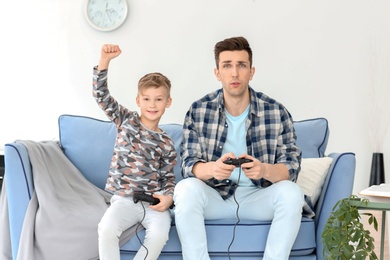 Happy dad and his son playing video games at home