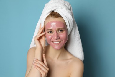 Young woman with pomegranate face mask on light blue background