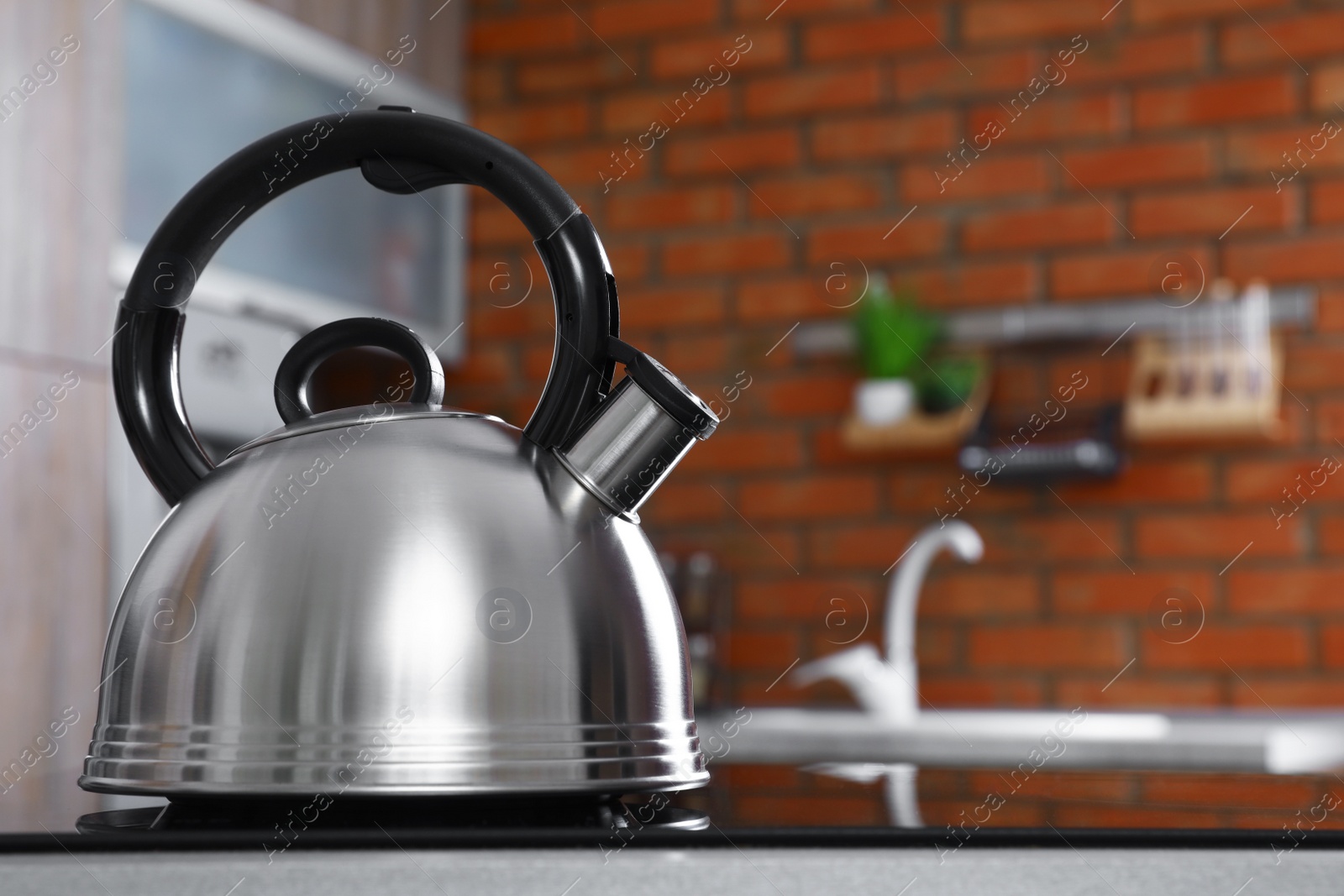 Photo of Modern kettle with whistle on stove in kitchen, space for text